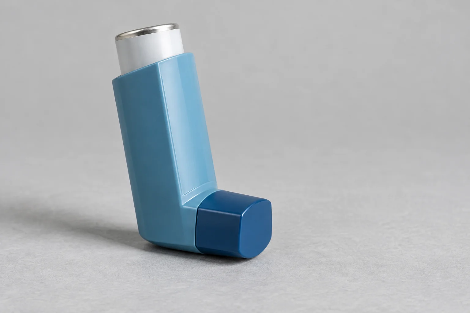 Unbranded capped inhaler on a neutral surface.