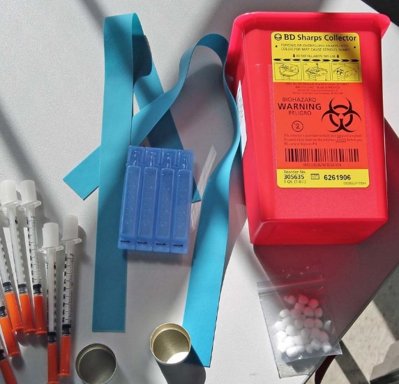 A sharps container with some other medical equipment