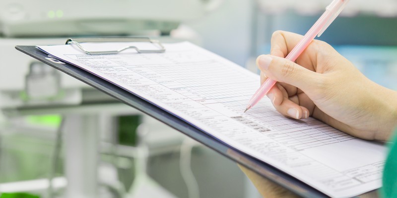 person writing on clipboard